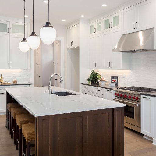 Modern white kitchen with island and pendant lights.