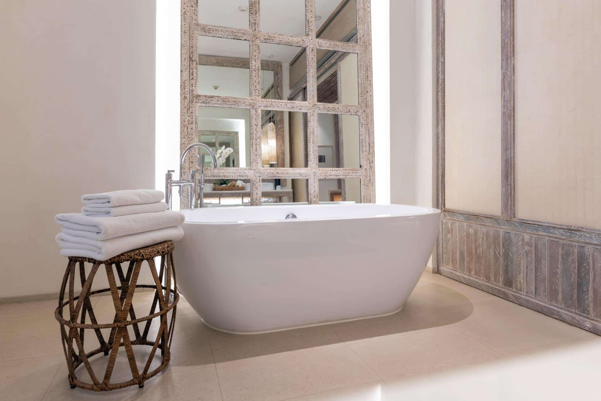 Freestanding bathtub with rustic mirror and towels