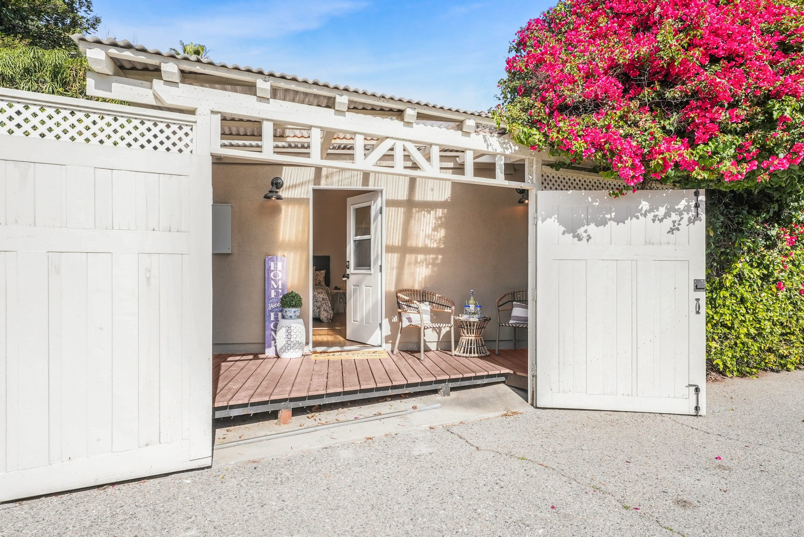 Charming patio entrance with white gate and pink flowers