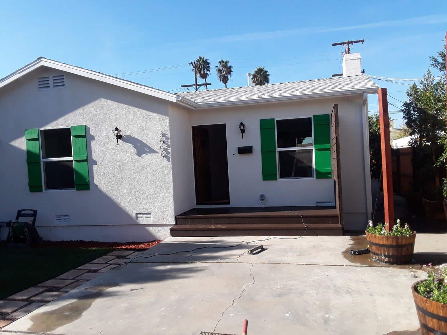 Renovated white stucco home exterior with green shutters, new wood composite porch steps, and barrel planter in North Hollywood