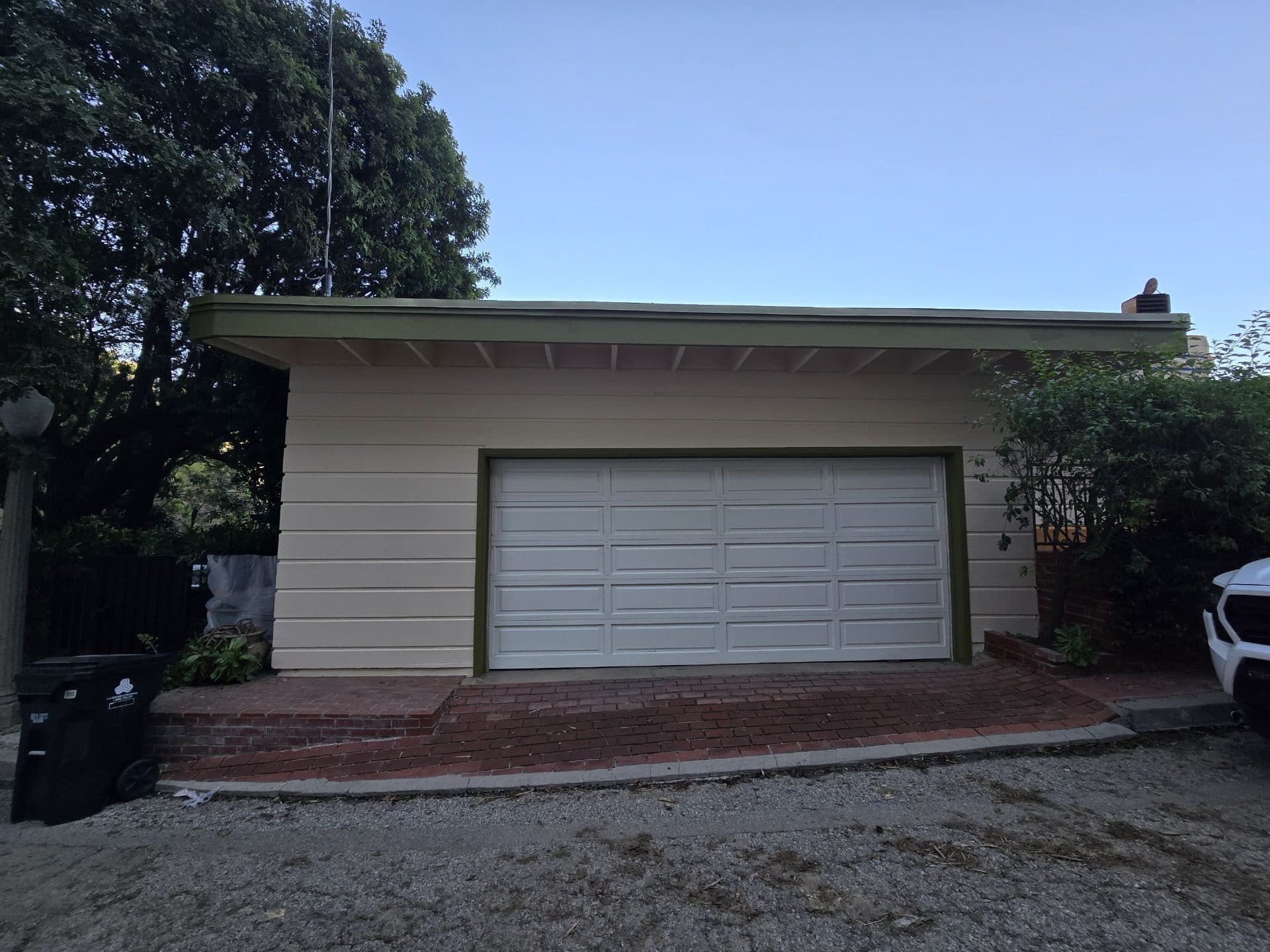 Detached garage with white panel door, brick apron, painted wood siding — Hollywood Contractor Corp