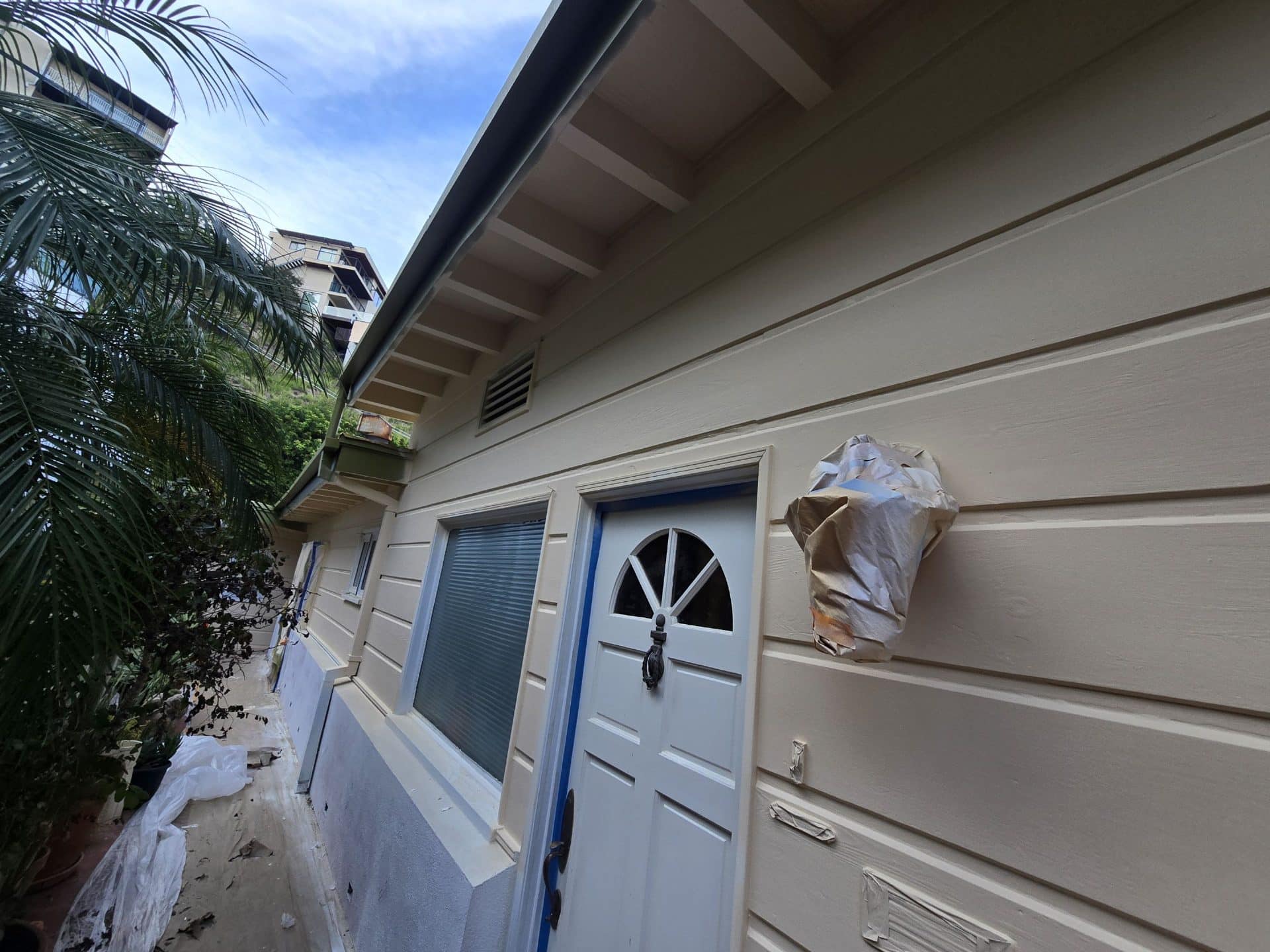 Freshly painted beige lap siding, white door trim, light fixture masked with paper — Hollywood Contractor Corp