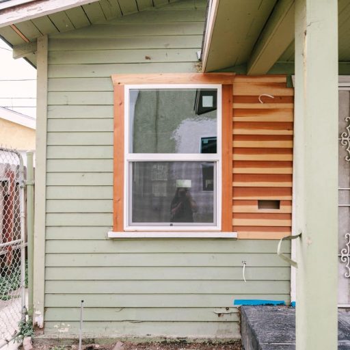 Renovated craftsman-style home exterior with fresh wood siding and orange-trimmed window in Los Angeles
