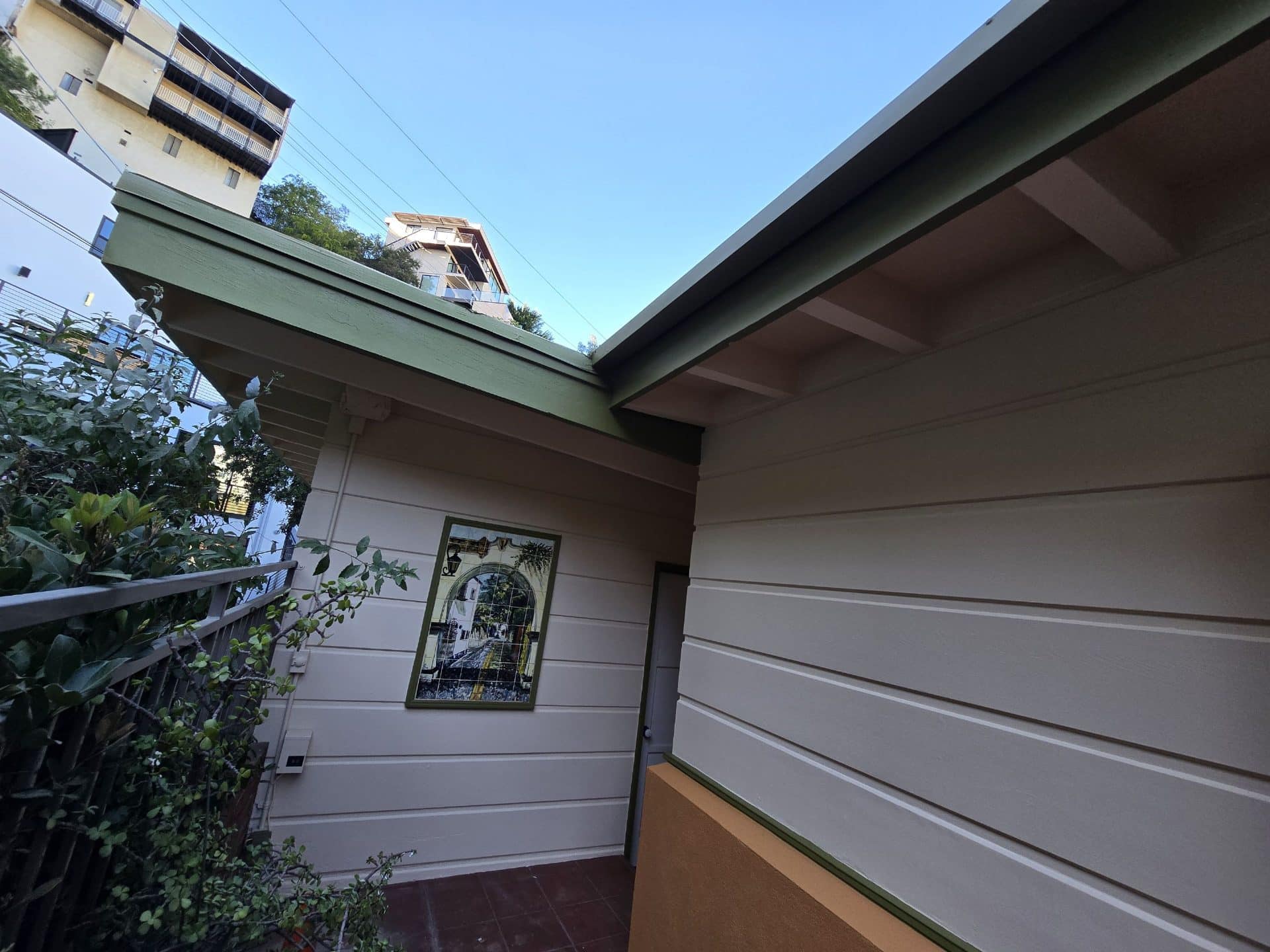 Painted lap siding, green trim eaves, exterior wall with framed artwork | Hollywood Contractor Corp Painted lap siding, green trim eaves, exterior wall with framed artwork — Hollywood Contractor Corp