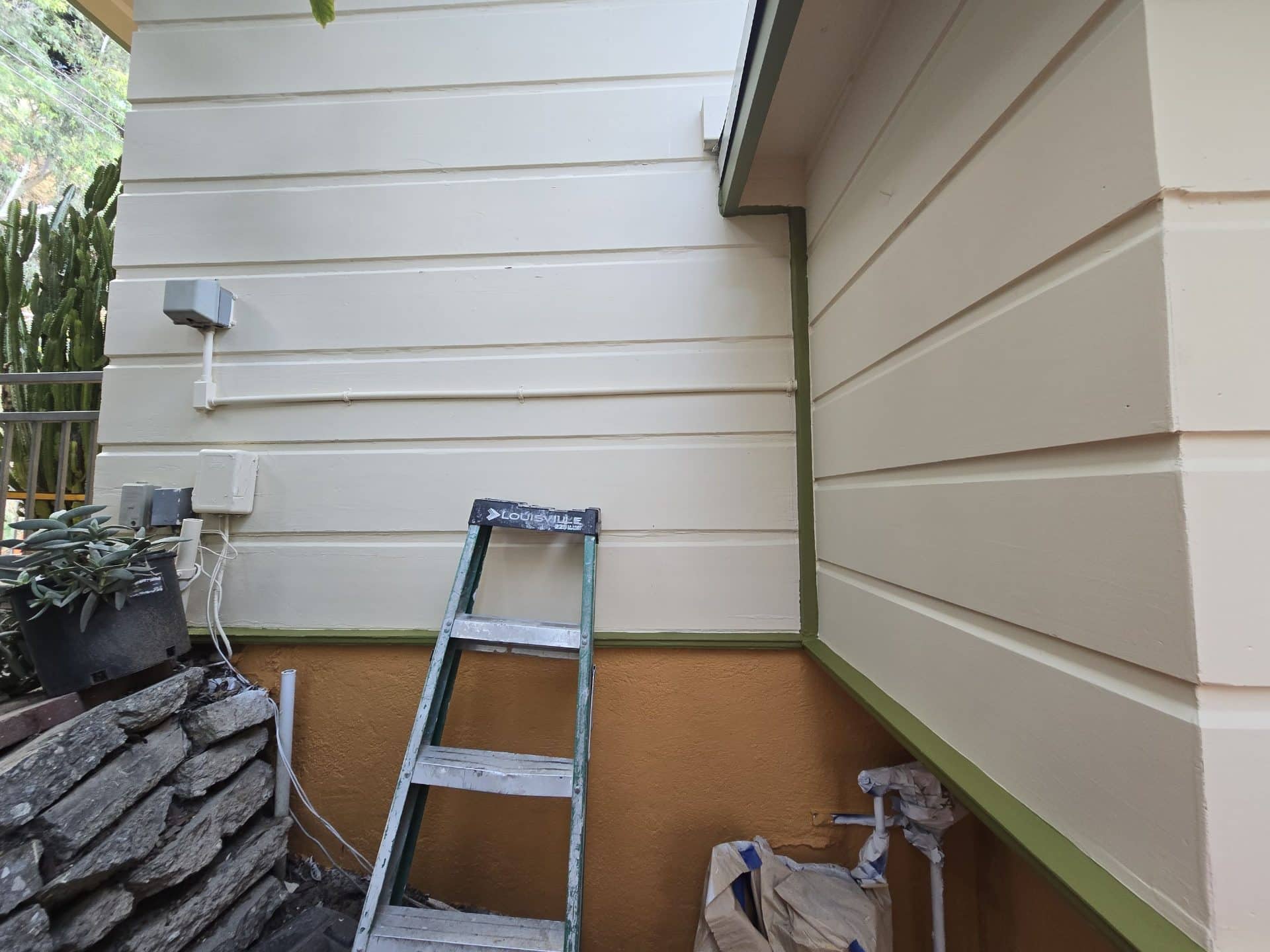 Painted lap siding, stucco base, green trim, step ladder, corner junction | Hollywood Contractor Corp Painted lap siding, stucco base, green trim, step ladder, corner junction — Hollywood Contractor Corp