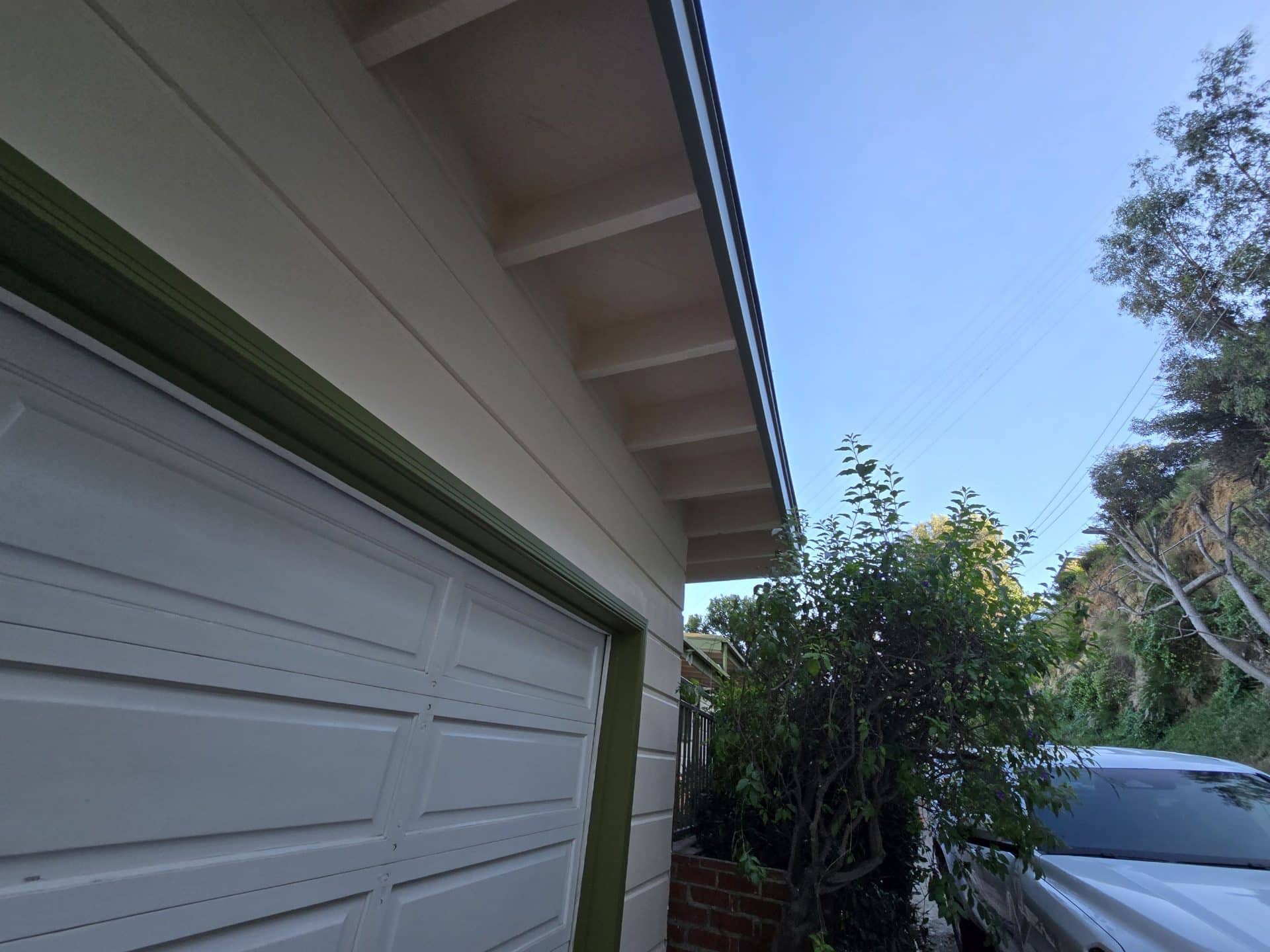 White painted eave soffit with exposed rafter tails and green trim — Hollywood Contractor Corp