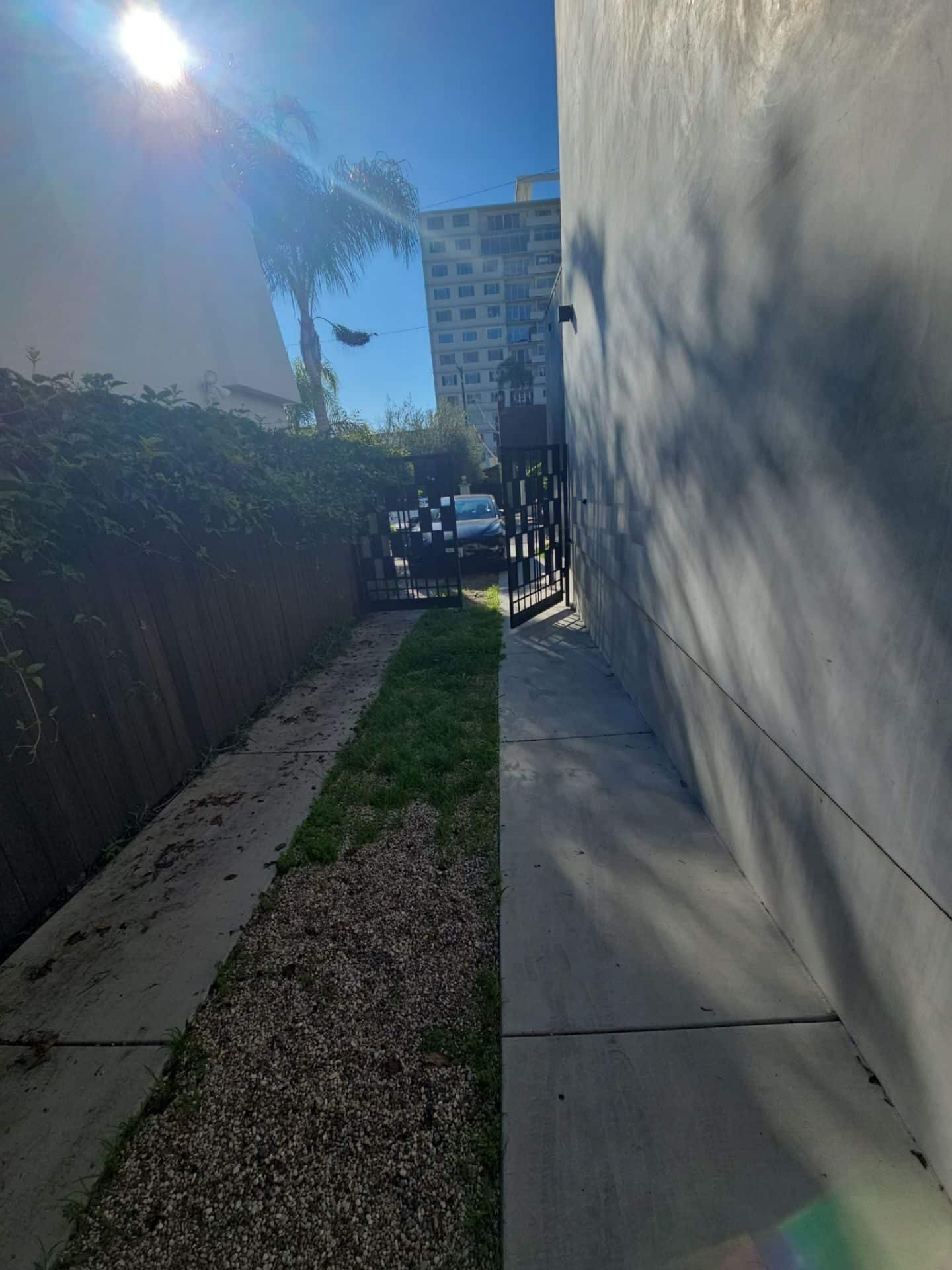 Narrow side yard with concrete pavers, gravel, grass strip, iron gate in West Hollywood | Hollywood Contractor Corp Narrow side yard with concrete pavers, gravel, grass strip, iron gate — West Hollywood — Hollywood Contractor Corp