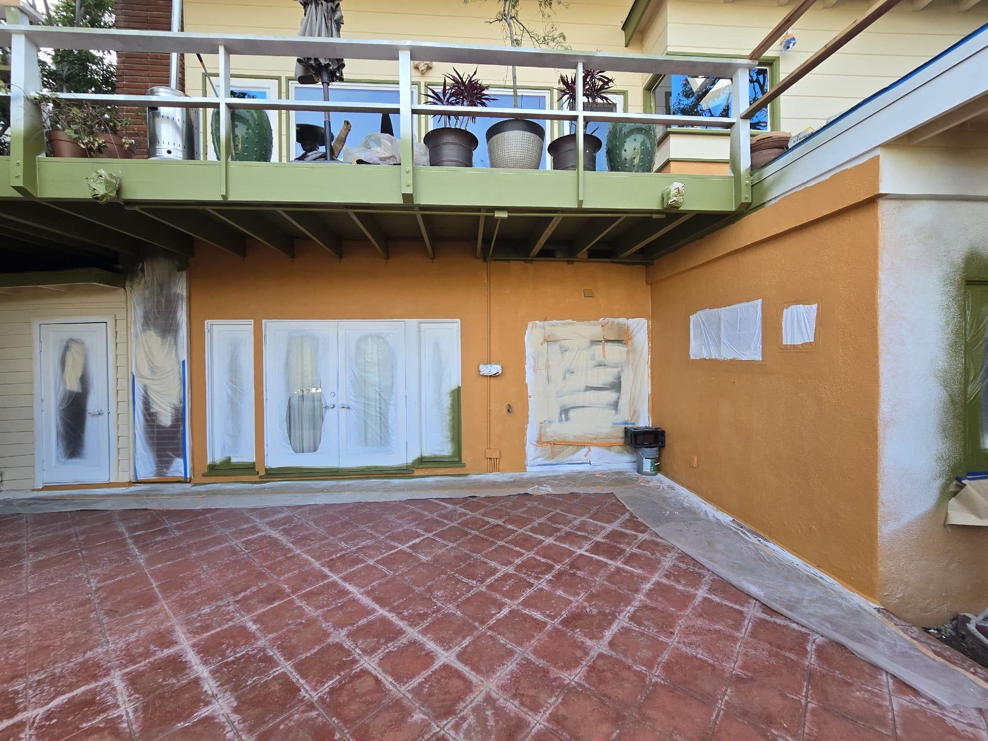 Stucco exterior walls painted orange, doors masked with plastic sheeting | Hollywood Contractor Corp Stucco exterior walls painted orange, doors masked with plastic sheeting — Hollywood Contractor Corp