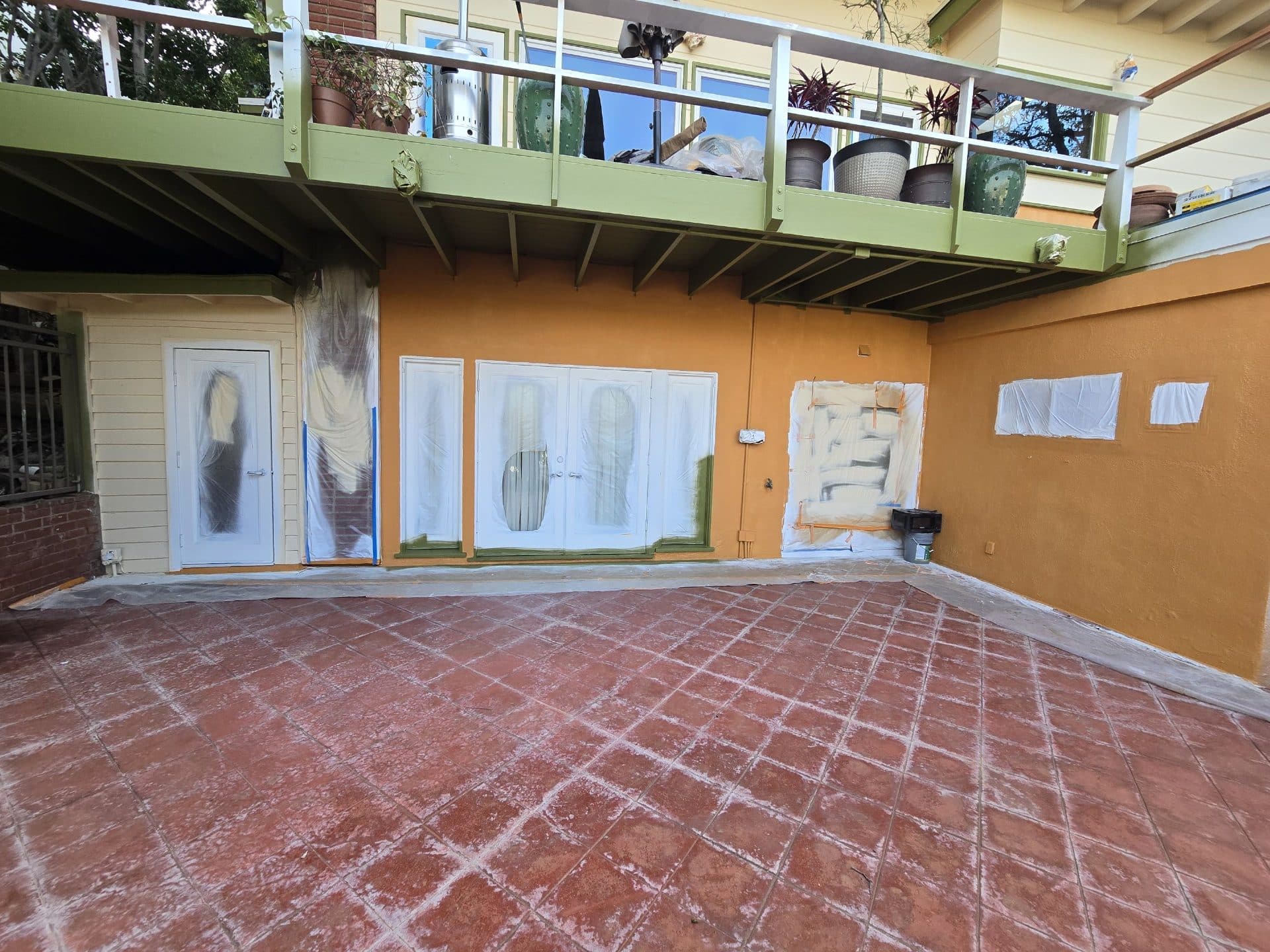 Stucco wall painted orange, doors masked with plastic sheeting, tiled patio | Hollywood Contractor Corp Stucco wall painted orange, doors masked with plastic sheeting, tiled patio — Hollywood Contractor Corp